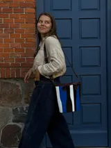 Matera de cuero con diseño de paneles verticales en combinación de colores azul, verde, marrón y bordó. Cuenta con dos asas cortas de cuero y estructura rígida.