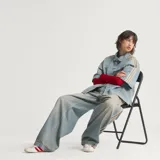 Camisa de jean de manga corta Adidas, confeccionada en 100% algodón, con diseño inspirado en la ropa de trabajo, cierre frontal con broches a presión, cuello camisero, un bolsillo en el pecho con solapa y las clásicas tres tiras de la marca en las mangas.