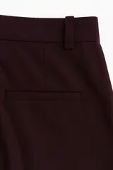 Pantalón sastrero de corte amplio con pinzas frontales y traseras, cierre con botón y corchete ocultos, bolsillos al bies y bolsillos decorativos traseros.