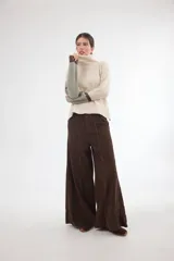 Pantalón sastrero de tiro medio confeccionado en pana de algodón, con corte amplio y diseño bicolor en los laterales. Presenta bolsillos delanteros y traseros, y un detalle de aplique con ojalillo metálico en la parte inferior de una de las piernas.