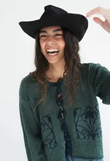 Saco de punto calado color crudo, con cierre frontal de tiras entrelazadas y diseño de flores negras en la parte frontal.