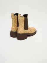 Botas estilo Chelsea de cuero vacuno rojo con grabado texturado tipo paisley, elásticos laterales negros y suela gruesa con taco de 5,5 cm.