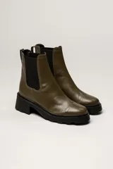 Bota tipo Chelsea de cuero color verde oliva, con paneles laterales elásticos negros y suela track de goma negra con taco cuadrado.