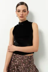 Top sin mangas de terciopelo negro con cuello alto.