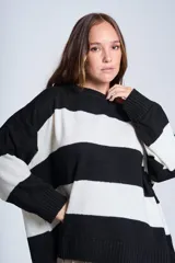 Sweater de punto con rayas horizontales anchas en blanco y negro. De corte amplio y relajado, brinda máxima comodidad sin perder el estilo. Su diseño atemporal lo convierte en una prenda versátil, ideal para combinar con jeans o pantalones para un look casual y abrigado en los días más frescos.