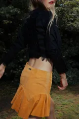 Minifalda de cuero color marrón oscuro, con fajón en la cintura y volados en el ruedo.