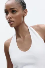 Top de punto con cuello halter y escote redondo profundo, sin mangas y corte ajustado.