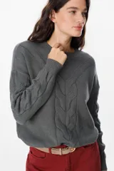 Sweater de punto negro con diseño de trenzas verticales en el frente y cuello redondo. Presenta un corte holgado con puños y ruedo acanalados.