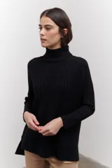 Polera de tejido de punto acanalado en color negro, con cuello alto y diseño de corte recto con largo asimétrico, más corto adelante y más largo atrás.