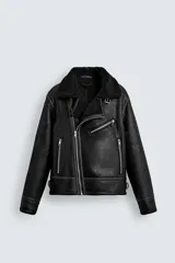 Cazadora de estilo biker con exterior de efecto cuero y forro interior de borreguillo. Presenta cierre frontal asimétrico con cremallera, cuello solapa con trabilla, bolsillos con cremallera y bajo ajustable con trabillas laterales.