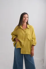 Camisa oversize de lino italiano color mostaza, con cuello camisero, cierre frontal de botones, bolsillo en el pecho y mangas largas con puños elásticos.