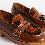 Mocasín de cuero vacuno negro con detalle de pieza de cuero con textura de cocodrilo y hebillas metálicas. Suela de caucho con plataforma.