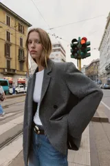Blazer de corte oversize en color gris jaspeado, con cuello solapa, hombreras y cierre frontal cruzado con botones. Cuenta con bolsillos delanteros con solapa.