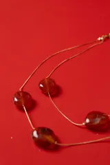 Collar doble de cadena dorada fina con cuentas marmoladas en tonos ámbar de formas orgánicas.