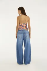 Pantalón jean de corte ancho y tiro medio, confeccionado en 100% algodón. Presenta cintura ajustable con cordón y detalles deshilachados en la parte superior.