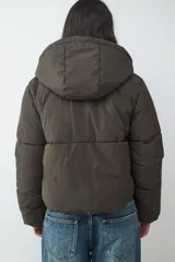 Campera puffer color verde militar, acolchada, con capucha y cierre frontal de cremallera.