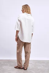 Camisa marrón de manga 3/4, con cuello clásico, botones frontales y un bolsillo en el pecho.