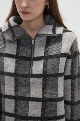 Sweater de tejido jacquard con diseño de cuadros, cuello solapa y cierre frontal parcial. Presenta un corte holgado y mangas largas.
