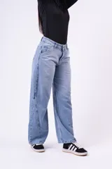 Jean de corte baggy con tiro medio, diseño de pierna ancha y costuras laterales decorativas. Presenta un lavado claro con efecto desgastado.