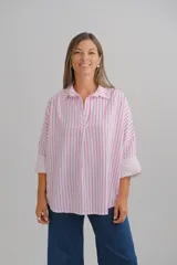 Blusa de corte holgado con estampado de rayas verticales en color fucsia y blanco. Presenta cuello camisero con escote en V y mangas largas con puños vueltos.