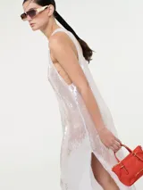 Vestido largo de corte recto con escote redondo y tirantes anchos, completamente cubierto de lentejuelas brillantes. Presenta tajos laterales en el ruedo.