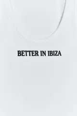 Musculosa de algodón blanca con escote redondo y el texto 'BETTER IN IBIZA' estampado en negro en el centro del pecho.