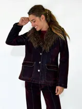Chaqueta de denim con efecto desgastado en tono azul oscuro y rojizo, con cuello de piel sintética desmontable, cierre frontal con botones metálicos y bolsillos frontales con solapa.