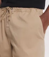 Bermuda masculina de sarga color blanco, con cintura elástica y lazo de ajuste. Presenta bolsillos laterales y una etiqueta decorativa aplicada en la parte inferior de la pierna.