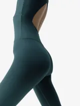 Mono largo deportivo de sujeción media-alta, color negro, con escote redondo y cierre frontal. Presenta diseño sin mangas, espalda abierta para mayor transpirabilidad y tejido compresivo en la cintura.