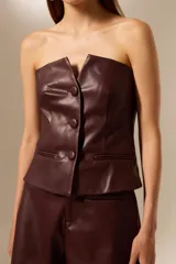 Top strapless de eco-cuero negro, con pinzas y botones frontales.