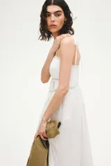 Vestido midi de algodón color blanco, con escote halter y breteles para atar en la nuca. Presenta detalles de encaje en el escote y la cintura, y falda fruncida con leve vuelo.