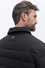 Campera puffer negra de líneas horizontales, con cuello camisero y cierre frontal oculto. Presenta un diseño minimalista con bolsillos laterales funcionales.