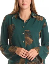 Camisa de crepe marca ABS Allen Schwartz, color marrón con estampado de hojas en tonos verdes y azules. Presenta cuello con solapa, cierre frontal con botones, mangas largas anchas y detalle de bordado con mostacillas en los hombros.