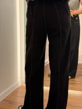 Pantalón de jean negro de corte recto y relajado, con costuras a contratono en color blanco. Presenta cintura con botón y cierre, bolsillos laterales y ruedo desflecado.