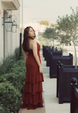 Vestido largo color ladrillo con breteles finos, escote en V y falda con volados en capas.