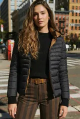 Campera reversible con diseño acolchado, cierre frontal y capucha. Un lado es de color negro y el otro de color tostado, con puños tejidos en color negro.