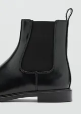 Botín Chelsea color negro de piel vacuna, con paneles elásticos laterales y tirador trasero.