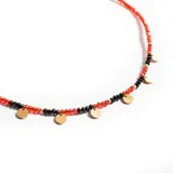 Gargantilla de cuentas facetadas rojas y negras con detalles dorados y dijes circulares dorados.