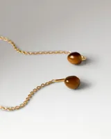 Par de caravanas colgantes de plata de ley con baño de oro de 18k, con piedra natural de ojo de tigre redonda de la que cuelga una fina cadena con barra decorativa.