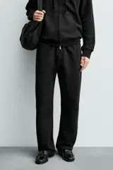 Pantalón jogger de corte regular fit y color negro, confeccionado en tejido compacto de algodón con interior de rizo. Cuenta con cintura elástica, bolsillos frontales y un bolsillo trasero de doble vivo.