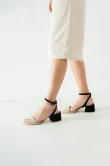 Sandalias de cuero color suela con taco cuadrado bajo y tira ajustable con hebilla en el tobillo.