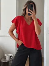 Blusa roja con escote en V y mangas cortas adornadas con volados en cascada, de corte holgado.