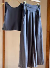 Pantalón palazzo negro de algodón, corte evasé, tiro alto, con bolsillos laterales, elástico en la espalda y faja ancha.