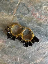 Aros de tipo argolla dorados decorados con pequeñas piedras naturales colgantes en tonos multicolores.
