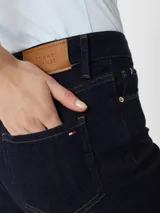Jeans azul oscuro de corte skinny, tiro alto, con cierre de botón y cremallera, cinco bolsillos y parche de Tommy Hilfiger en la parte posterior.