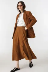 Falda midi de gamuza color marrón, con cintura alta, elástico en la parte trasera, cierre lateral y tajo lateral.