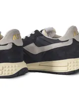 Championes Autry modelo Reelwind Low, inspirados en el estilo runner de los años 80. Presentan un diseño en color negro con detalles en gris claro, confeccionados en una combinación de ante y malla transpirable. Incluyen el logo de la marca en el lateral y en la lengüeta, con una suela de goma amortiguada de aspecto vintage.