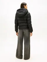 Campera térmica de plumón Tommy Hilfiger, color negro, confeccionada en nailon ligero con acabado repelente al agua. Presenta capucha fija, cuello levantado, cierre frontal de cremallera y puños tejidos acanalados.