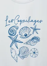 Remera de manga corta color blanco con cuello redondo y diseño recto. Presenta un estampado frontal en tonos azules con ilustraciones de caracoles y la inscripción "Les Coquillages".