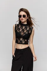 Top de encaje blanco con cuello alto y diseño sin mangas, de corte ajustado.